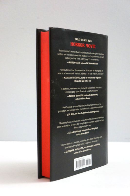 The back cover of a hardcover book, standing upright against a light gray background. The cover is black with white text and a red spine edge visible on the left.