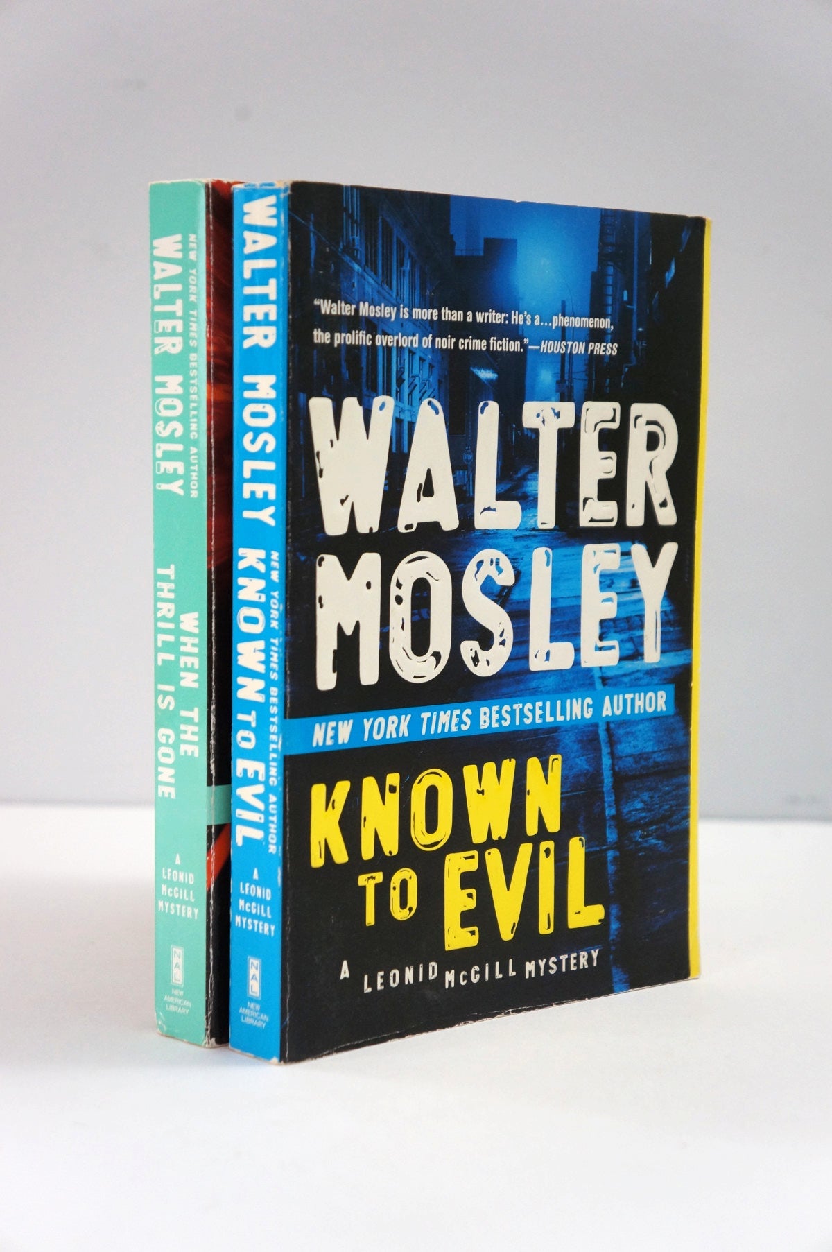 Two books by Walter Mosley on a white surface with a gray background