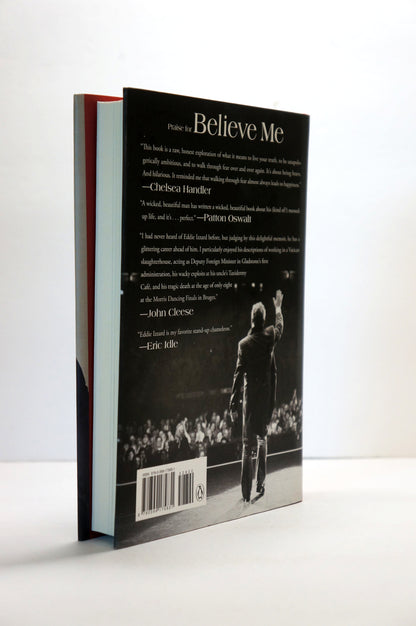 The back cover of a hardcover book titled 'Believe Me' by Eddie Izzard, standing upright on a white surface against a white background.