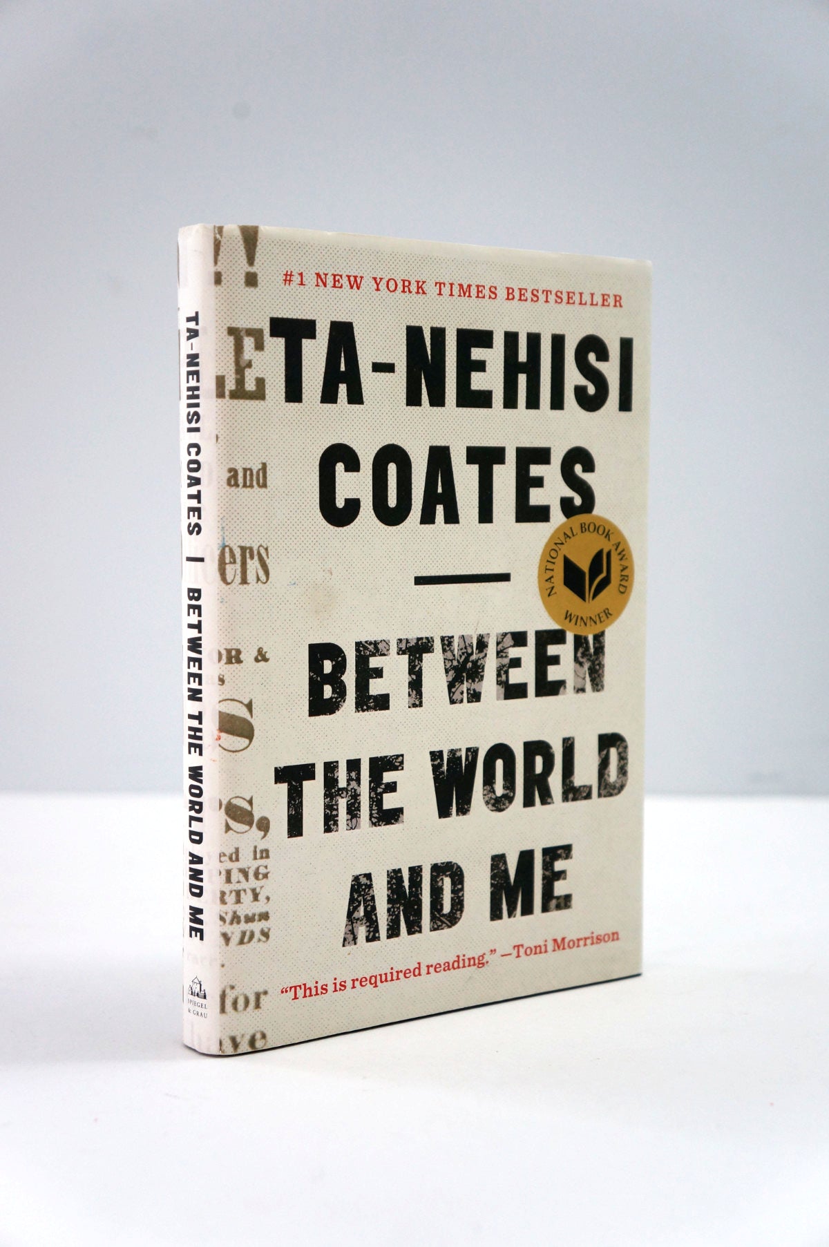 Book titled 'Between the World and Me' by Ta-Nehisi Coates on a gray background