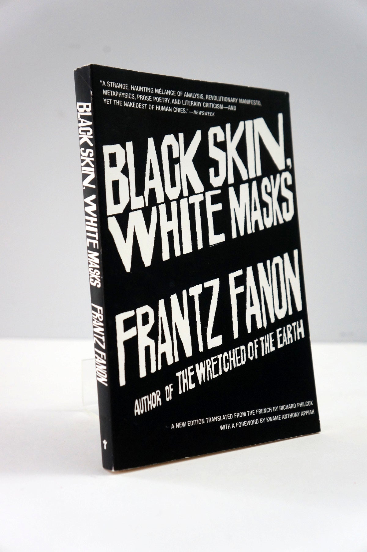 Book titled 'Black Skin, White Masks' by Frantz Fanon on a white background