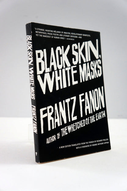 Book titled 'Black Skin, White Masks' by Frantz Fanon on a white background