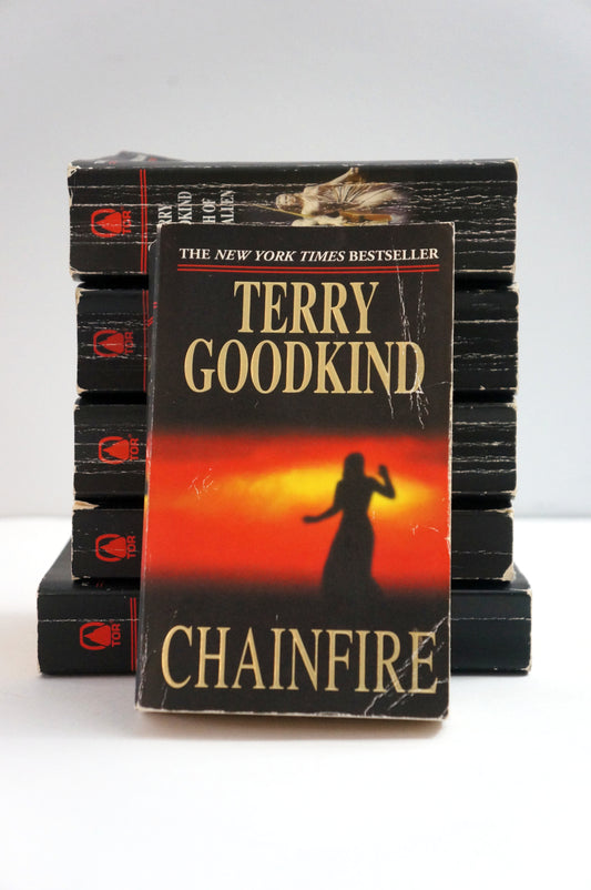 A vintage paperback copy of Terry Goodkind's 'Chainfire' book standing in front of a stack of identical copies on a white surface against a light gray background.