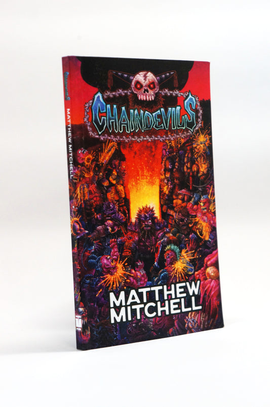 The book cover of 'Chainsawdevils' by Matthew Mitchell, featuring a highly detailed, colorful fantasy illustration of demonic creatures in a fiery red and orange landscape, shown standing upright on a white background.