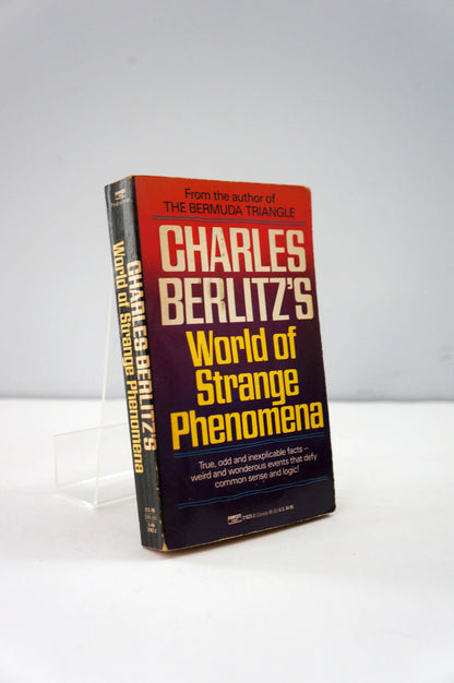 Book titled 'World of Strange Phenomena' by Charles Berlitz on a white background