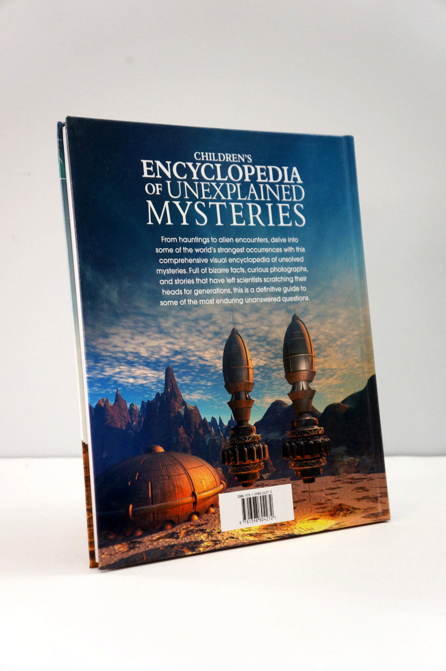 Book titled 'Children's Encyclopedia of Unexplained Mysteries' on a white background