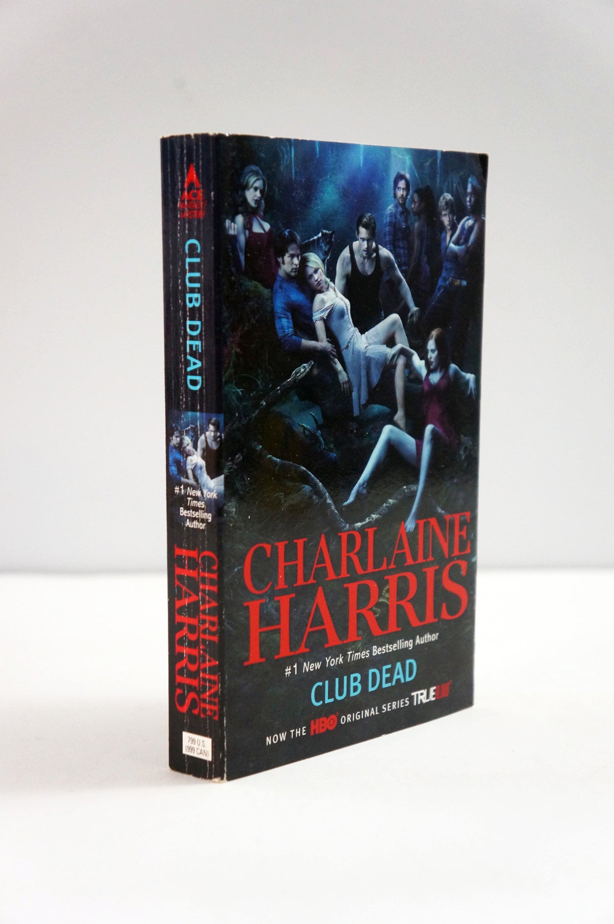 A paperback titled 'Club Dead' by Charlaine Harris, standing upright against a plain light background. The cover and spine feature dark blue and black artwork with red and white text.