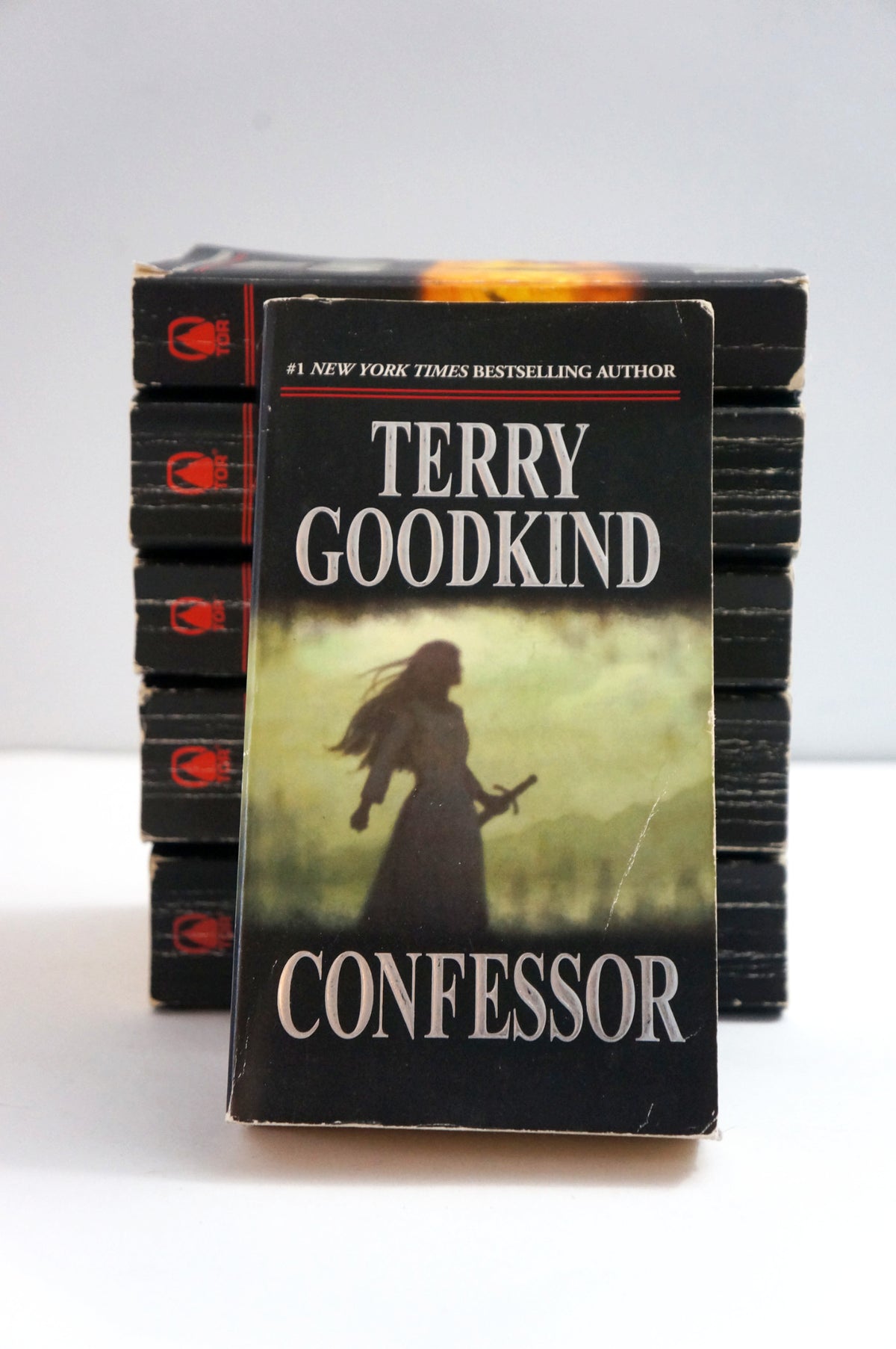 A stack of paperback books of Terry Goodkind's 'Confessor' series, with the front book standing upright to show the cover, photographed against a plain light background.
