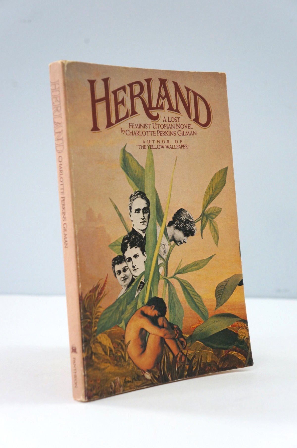 Book titled 'Herland' with cover art featuring women and a child among plants on a light gray background.