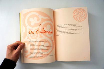 Open book with decorative text and a hand holding it on a light background