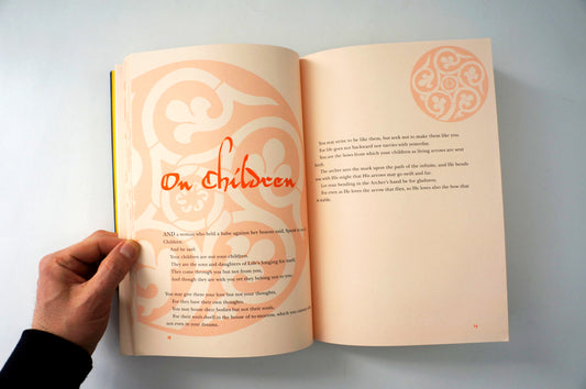 Open book with decorative text and a hand holding it on a light background