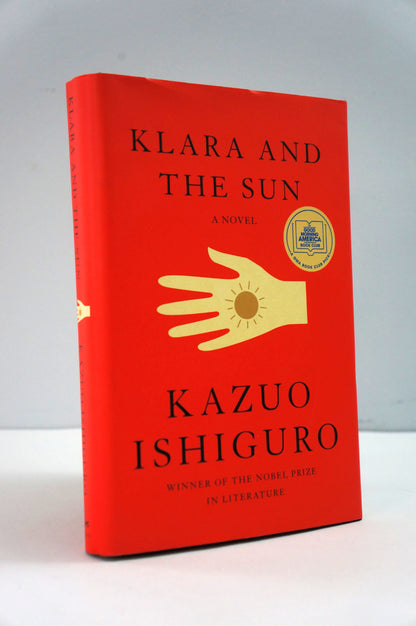 Book titled 'Klara and the Sun' by Kazuo Ishiguro with a red cover and gold hand illustration.
