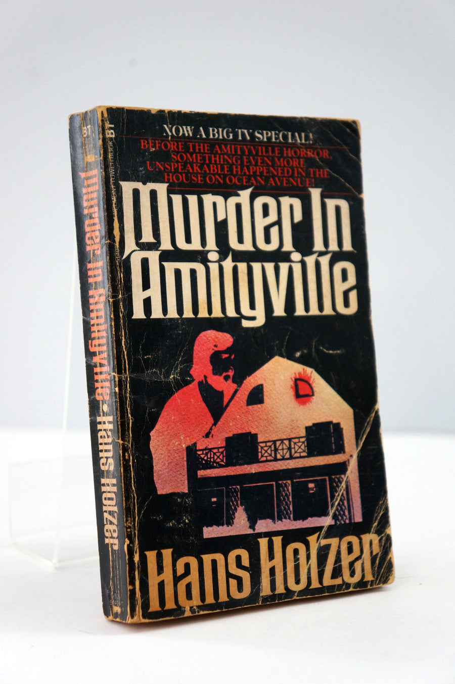 Book titled 'Murder in Amityville' by Hans Holzer on a white background