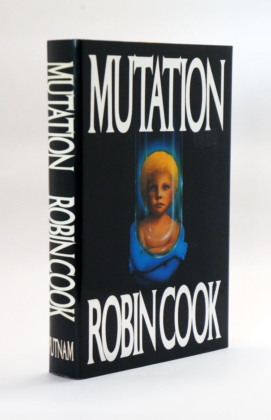 A hardcover book titled 'Mutation' by Robin Cook, standing upright at a slight angle. The cover is predominantly black with large white title text and a central illustration of a blue-clothed figure with yellow hair.
