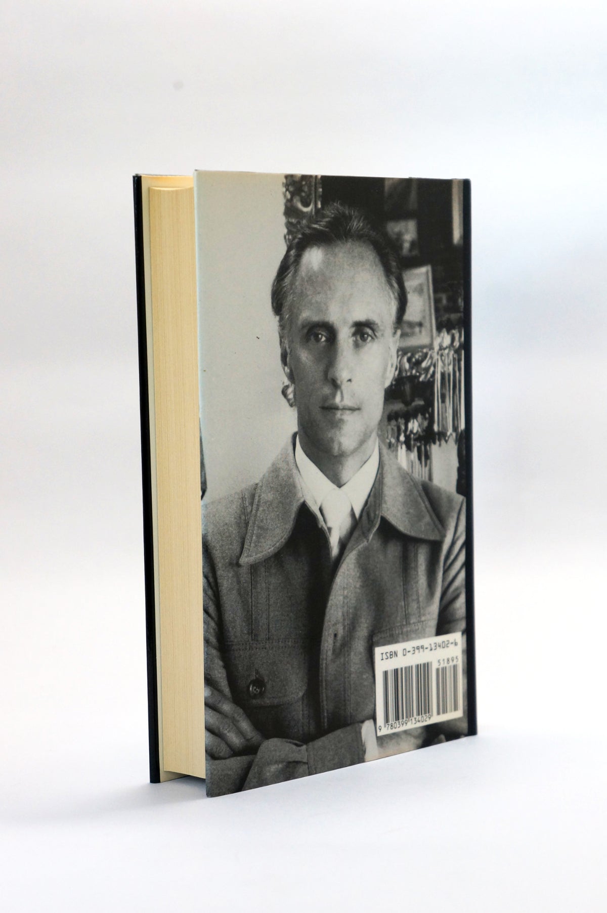 A hardcover book standing upright on a white studio background, showing a black-and-white portrait photograph on the cover and a barcode sticker near the lower right.