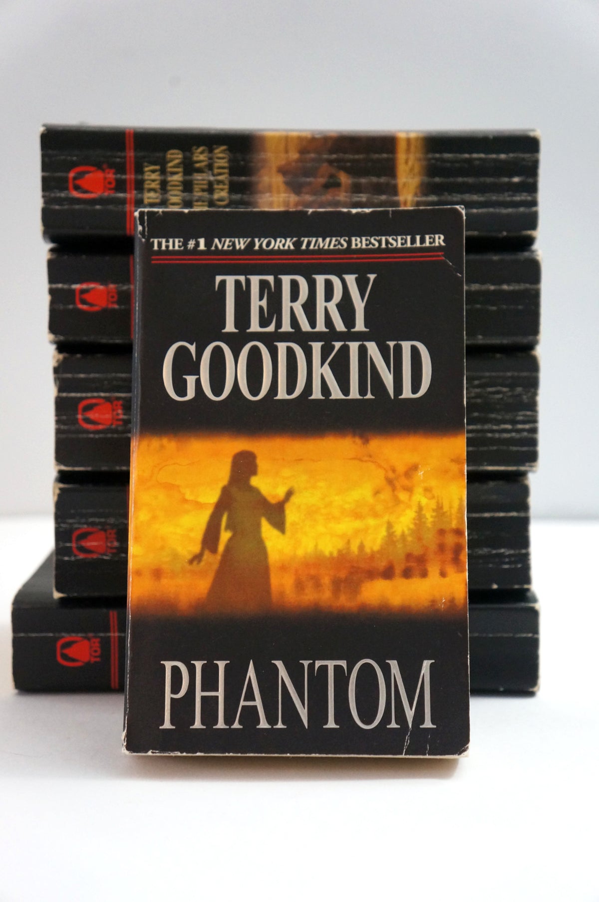 A vintage paperback copy of Terry Goodkind's 'Phantom' New York Times bestseller, displayed in front of a stack of identical books on a white surface.