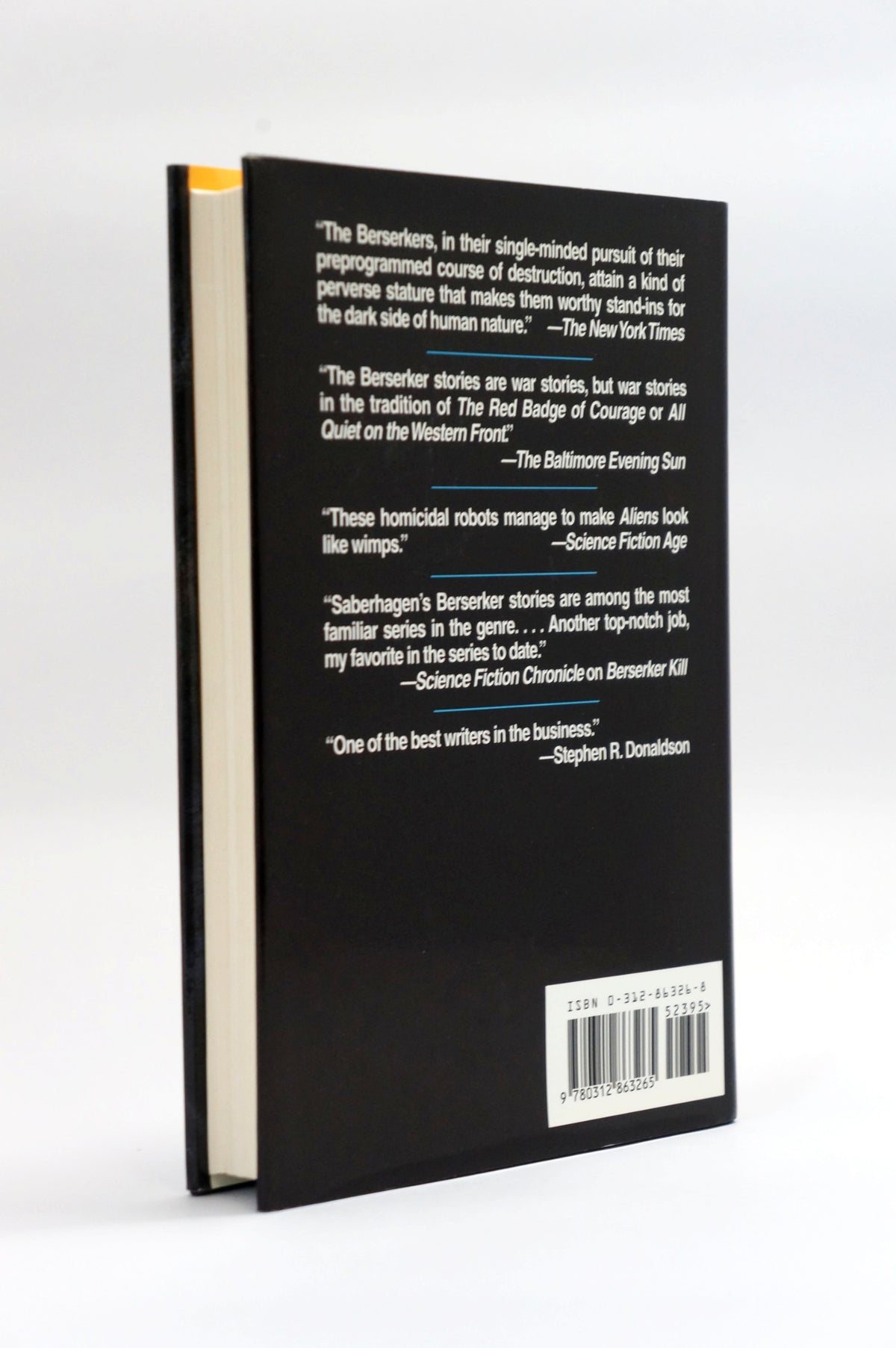 The back cover of a black hardcover book standing upright on a white background, featuring white review quotes, a barcode, and a small yellow accent on the left edge.
