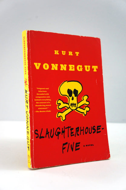Book cover of 'Slaughterhouse-Five' by Kurt Vonnegut with a red background and yellow skull and crossbones design.