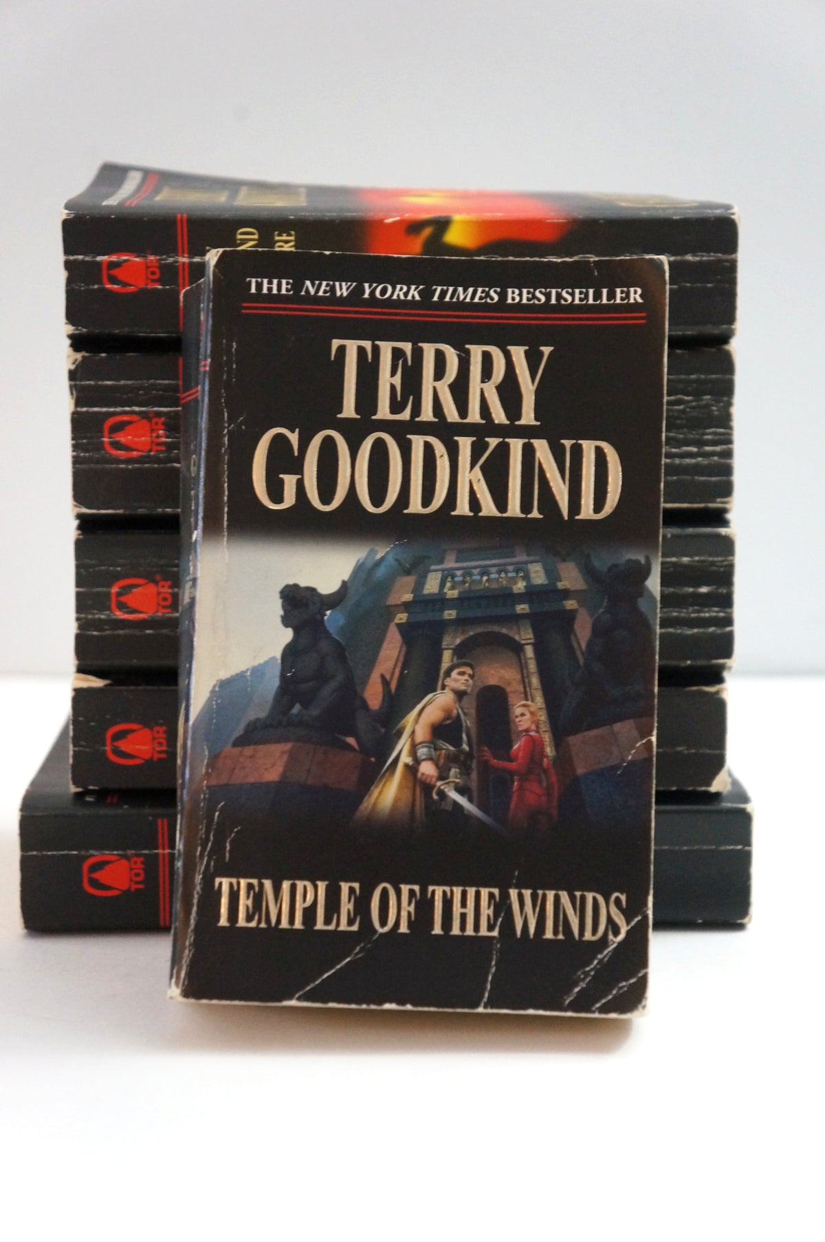 A vintage paperback book of Terry Goodkind's 'Temple of the Winds' stands in front of a stack of identical copies on a white background.