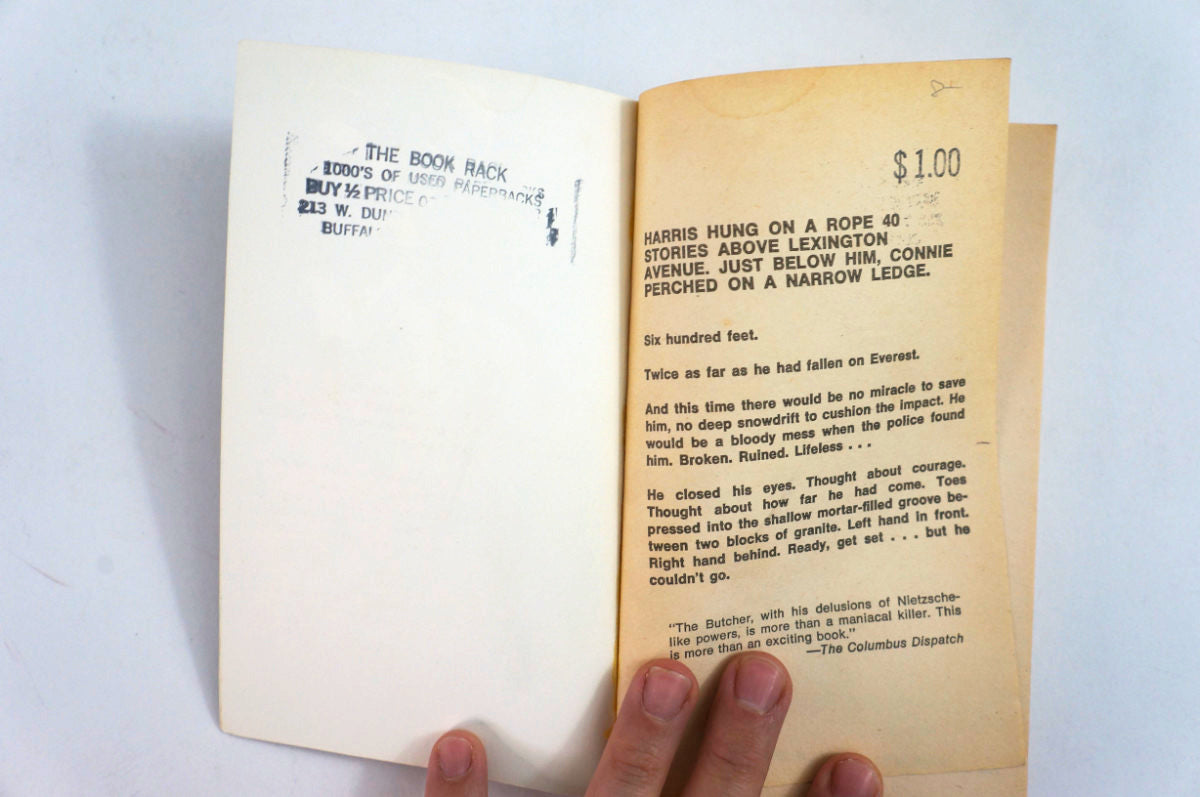 An open vintage book showing two yellowed pages with printed text and handwritten notes, held by a hand against a plain white background.