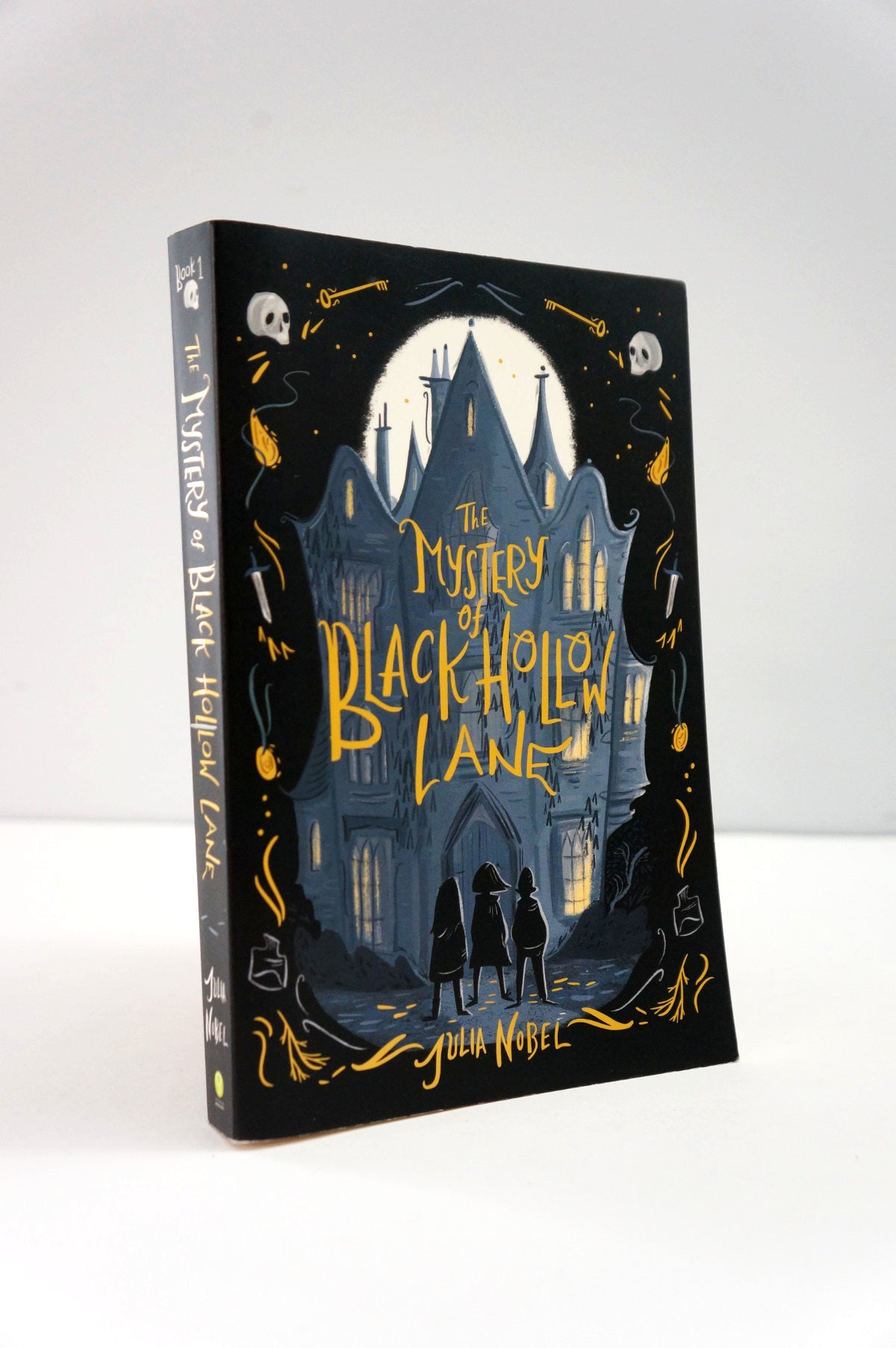Book cover of 'The Mystery of Black Hollow Lane' with a dark castle and silhouettes on a black background.