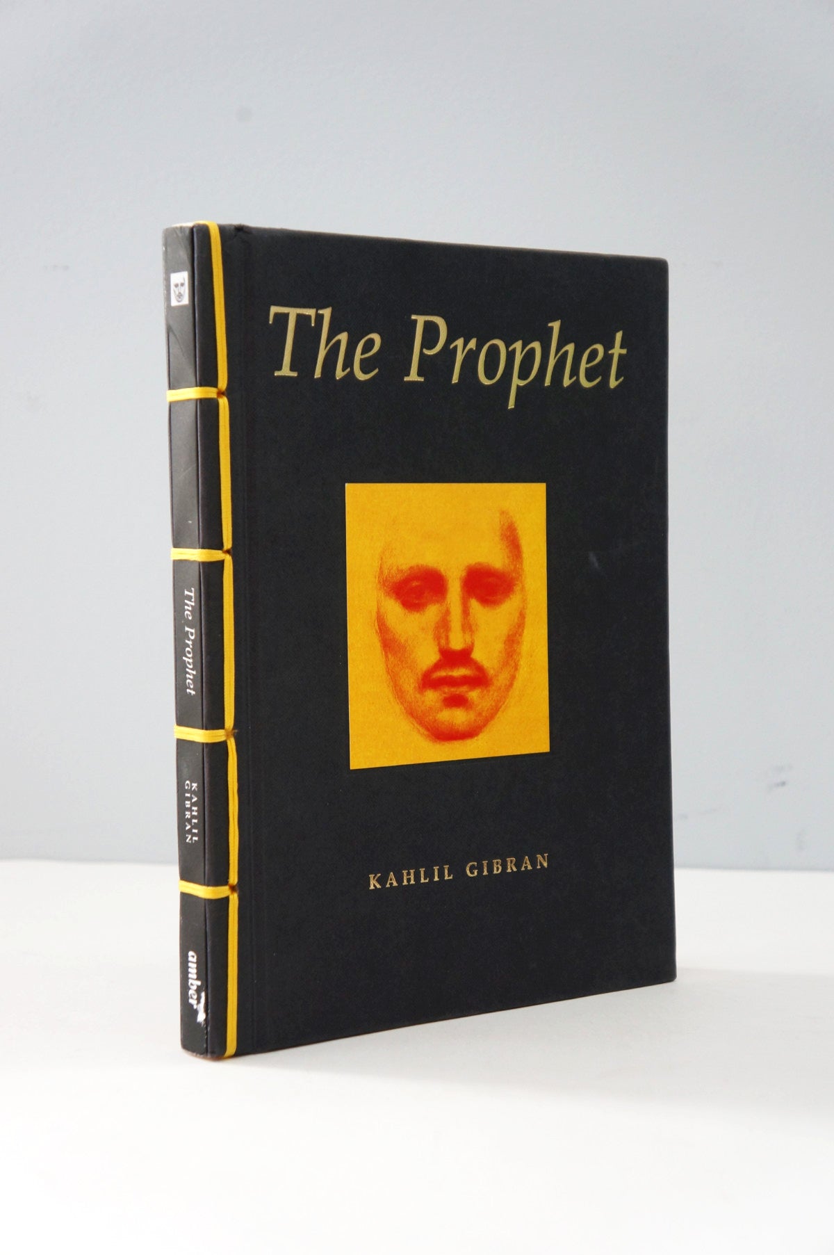 Book titled 'The Prophet' by Kahlil Gibran with a yellow face illustration on a black cover.
