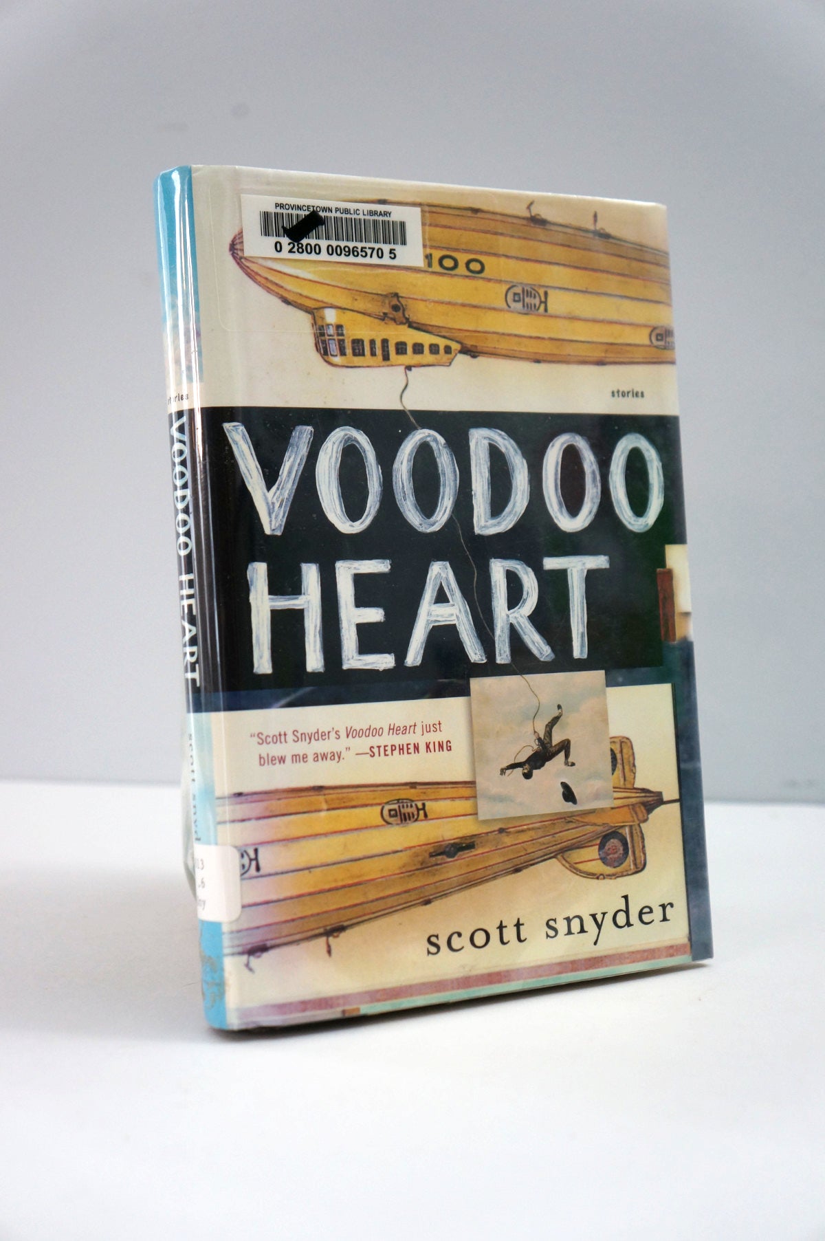 Book cover of 'Voodoo Heart' by Scott Snyder with airplane illustration on a gray background
