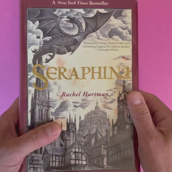 video of a hardcover copy of Seraphina by Rachel Hartman with a dragon and castle illustration on the cover 