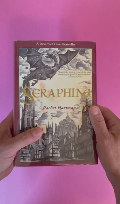 video of a hardcover copy of Seraphina by Rachel Hartman with a dragon and castle illustration on the cover 