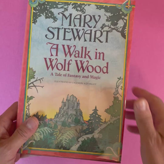 Video of a hardcover copy of A Walk in Wolf Wood by Mary Stewart featuring a painted fantasy scene with a castle on the cover.